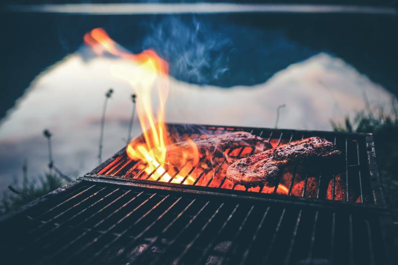 Deux steaks en train de cuire sur un grill à feu ouvert.
